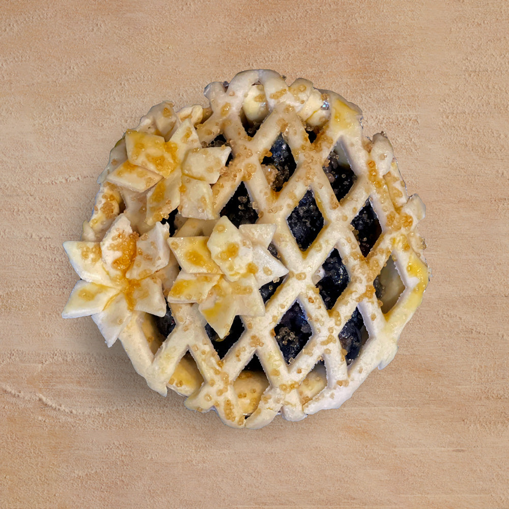 Mixed berry pie with decorative lattice crust on a wooden surface
