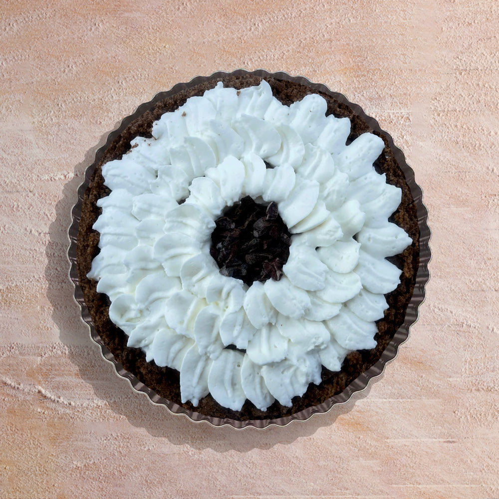 Chocolate pie with fresh whipped cream on a beige surface